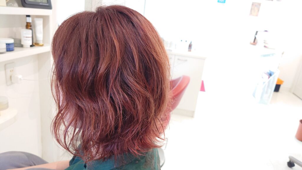 ピンクカラーのミディアムパーマスタイル