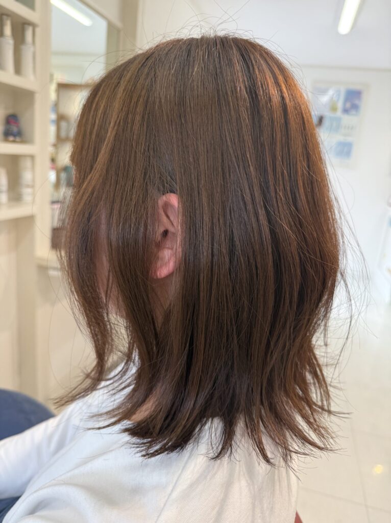 毛先に軽い動きとくびれをつけた柔らかなブラウンのミディアムレイヤースタイル