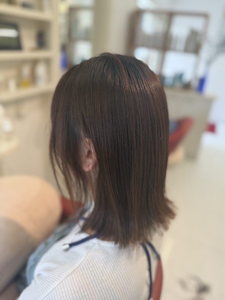耳まわりをすっきり見せた外はねボブの横後ろ姿。落ち着いたアッシュベージュの色合い