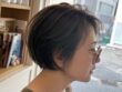 顔まわりのフェイスフレーミングとトップのハイライトを入れたオリーブベージュの前下がりショートボブ