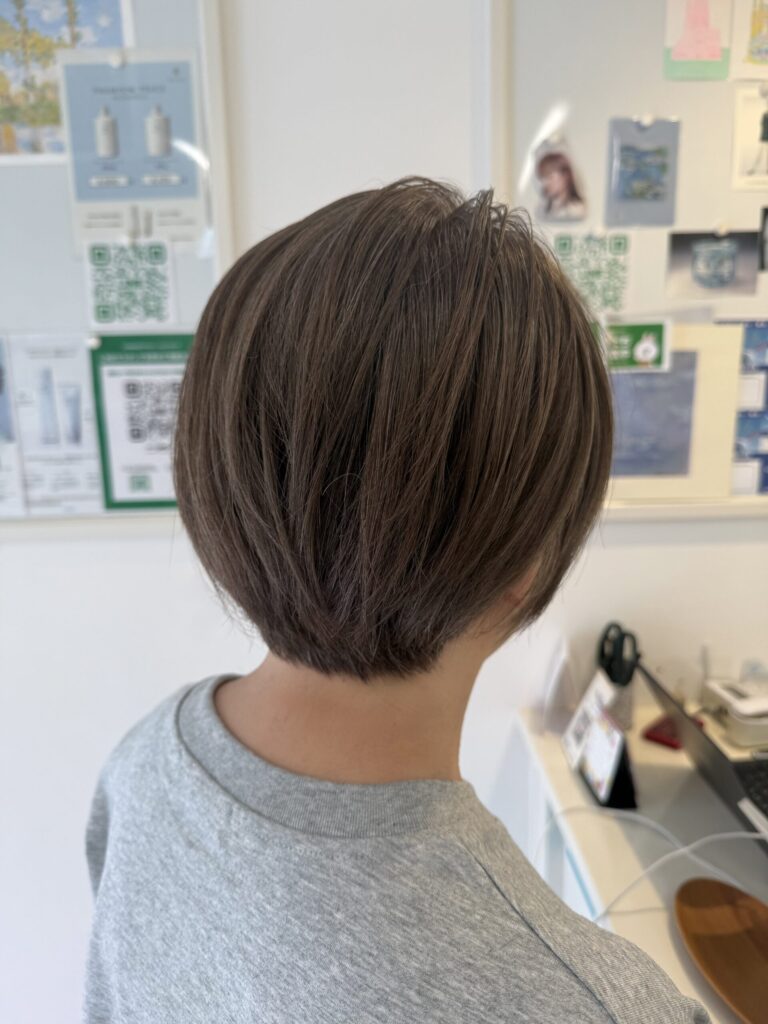 白髪をファッションカラーのミントグレージュで染めた丸みショートボブの後ろ姿