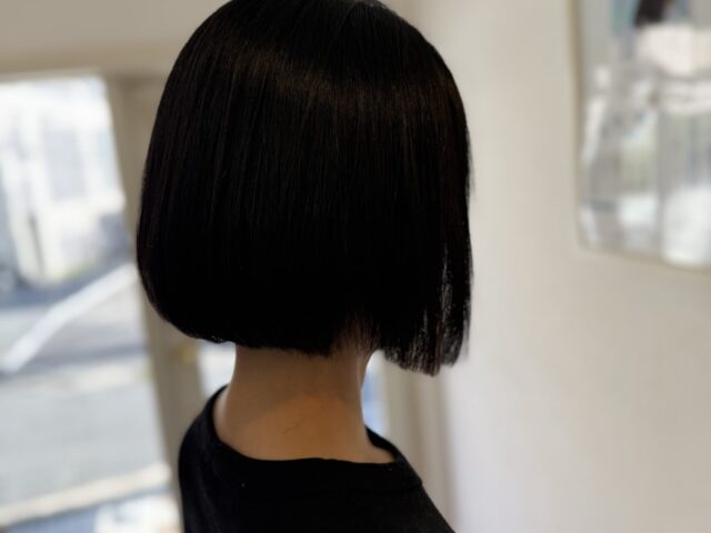 黒髪のコンパクトボブを斜め後ろから見た仕上がり。なめらかな毛流れとすっきりした襟足まわり