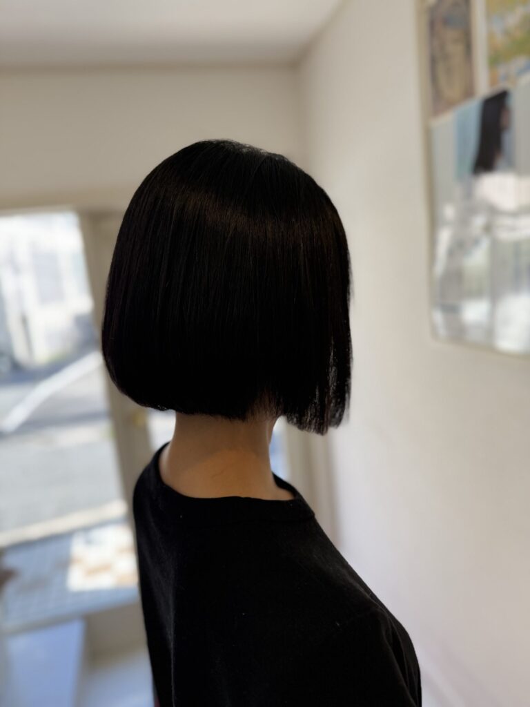 黒髪のコンパクトボブを斜め後ろから見た仕上がり。なめらかな毛流れとすっきりした襟足まわり