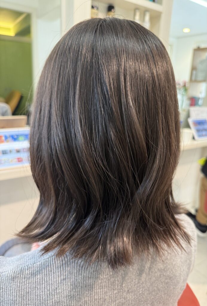 落ち着いた髪色の外はねボブの後ろ姿。なめらかな表面と肩まわりで外へ向かう毛先