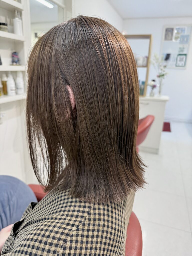 オリーブベージュの色合いが見える外はねボブの左側。顔まわりの毛束とほどよく厚みのある裾