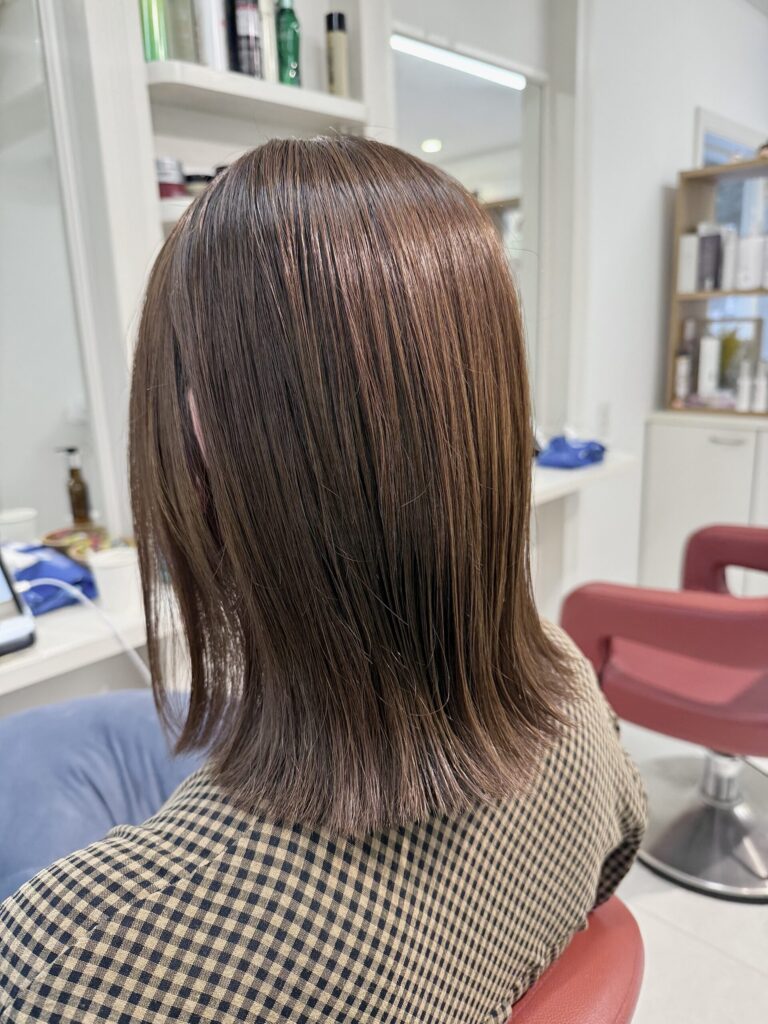 肩下の外はねボブを左斜め後ろから見た仕上がり。ぱつっとした毛先とやわらかなオリーブベージュ