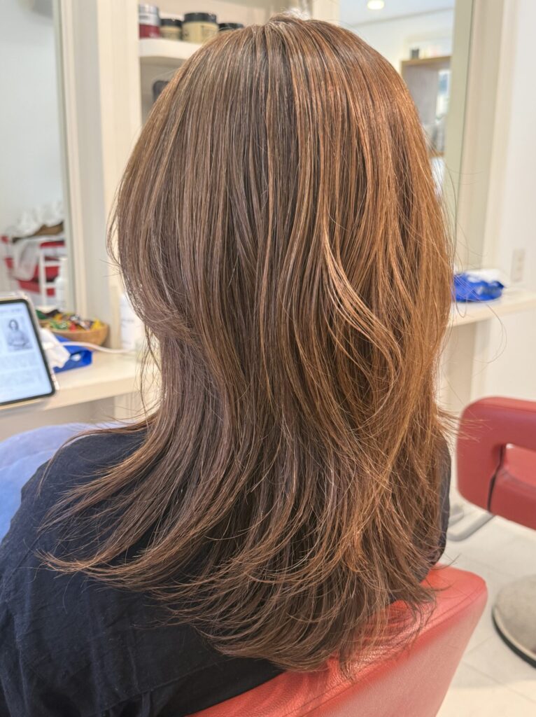毛量とレイヤーのバランスを調節したロングヘアの後ろ姿。軽やかに動く毛先とベージュカラー