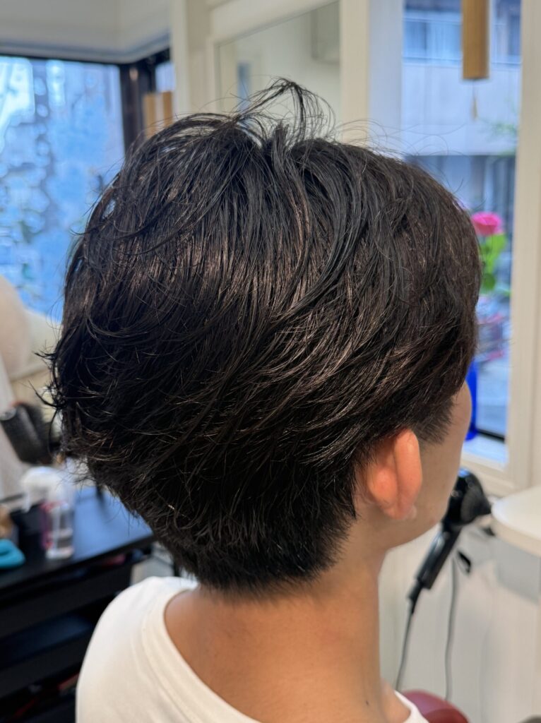 メンズパーマを右斜め後ろから見たスタイル。後頭部に重なるやわらかな毛流れと、すっきりした耳まわり