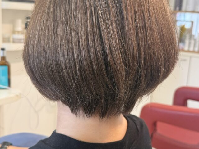 オリーブベージュのショートボブの後ろ姿。ふっくらとした丸みと首元に沿うすっきりした襟足