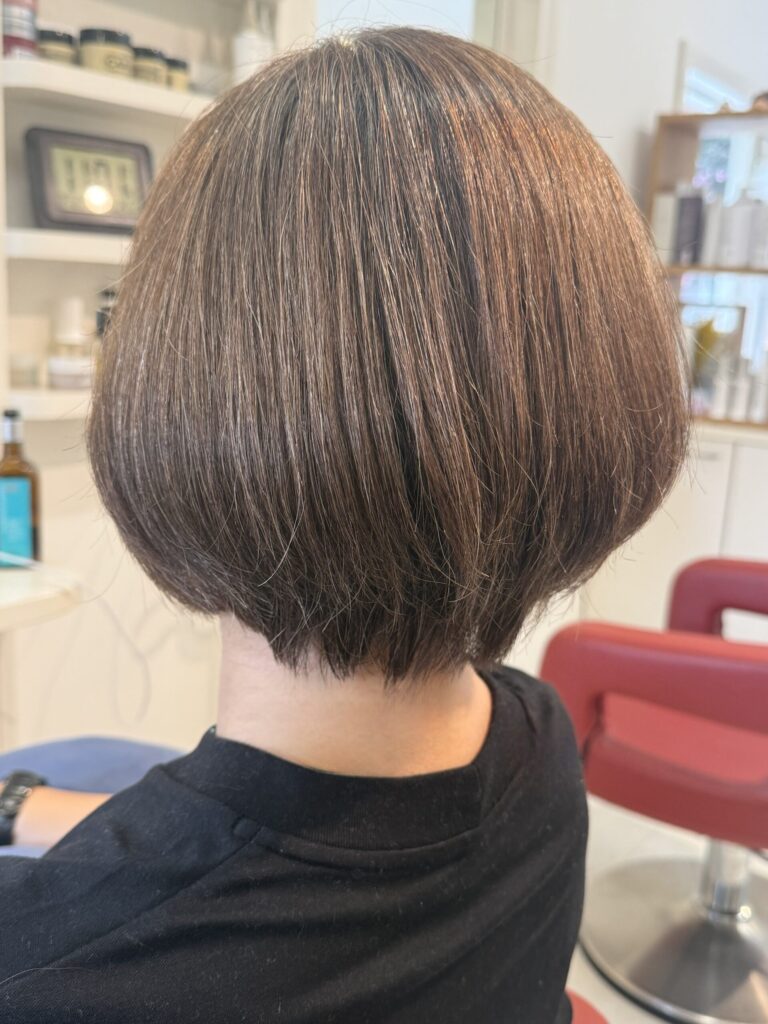 オリーブベージュのショートボブの後ろ姿。ふっくらとした丸みと首元に沿うすっきりした襟足
