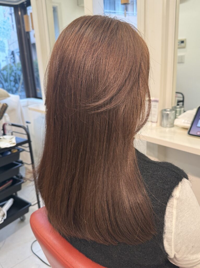 明るめショコラブラウンのロングヘア。顔まわりから後ろへ流れるレイヤーと、まとまりのある毛先